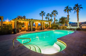 a swimming pool at night at a resort with palm trees